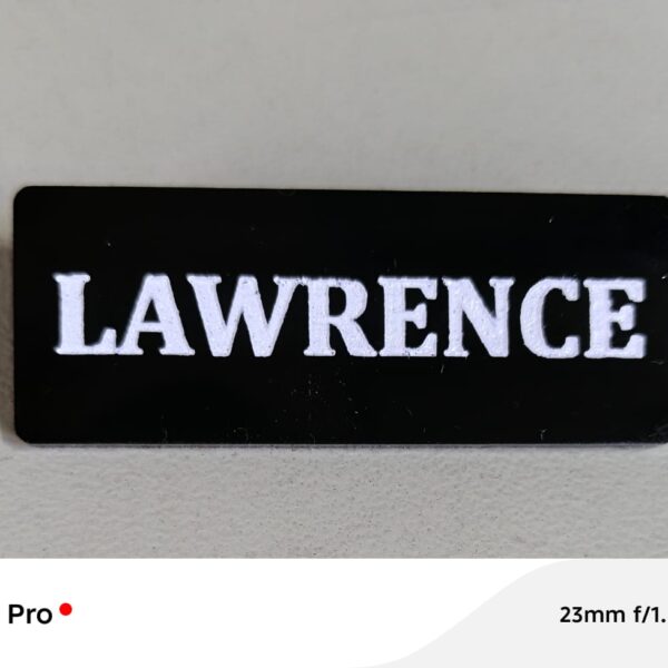 Custom engraved black name badge with white text LAWRENCE